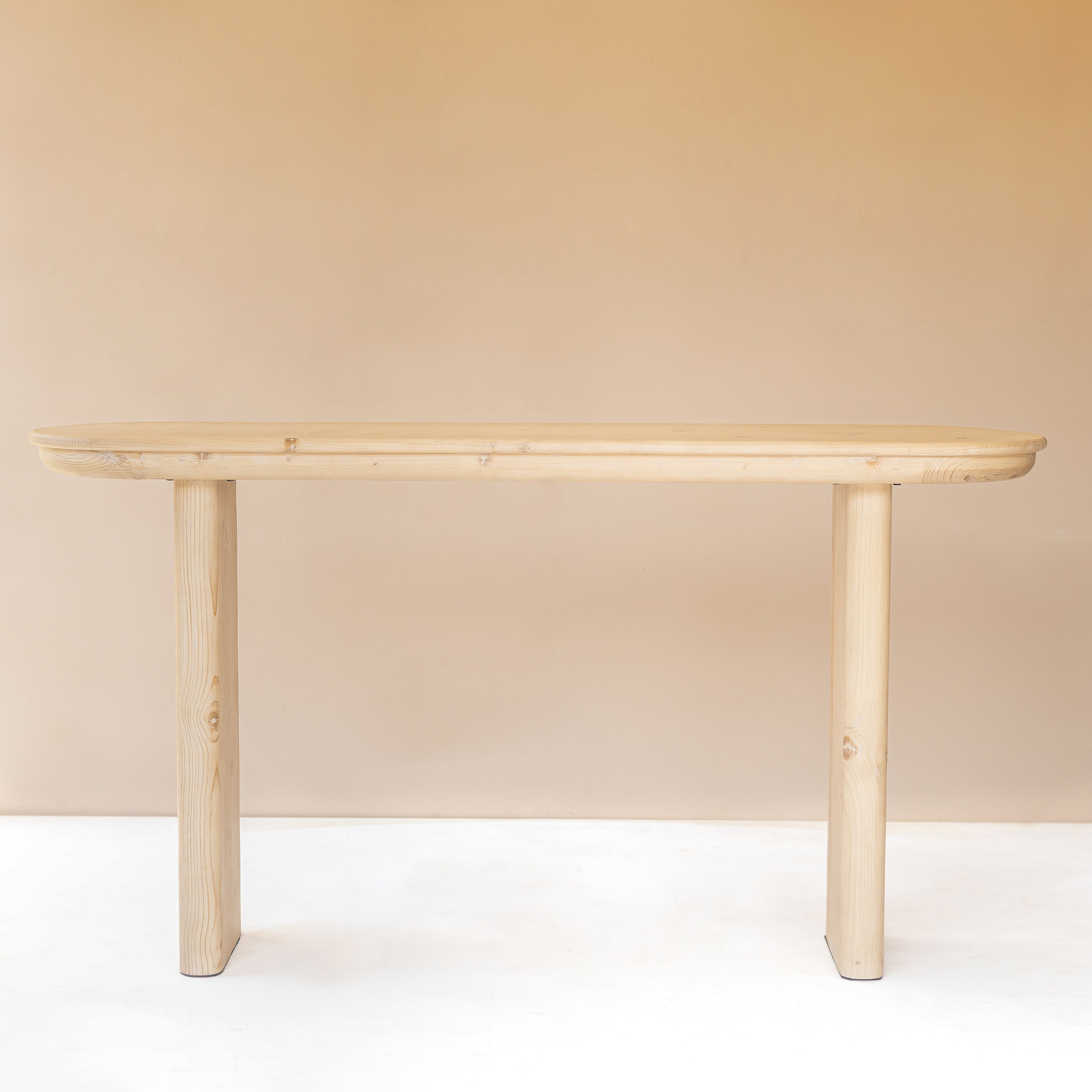 A simple, elegant console table made of pine wood with a natural finish, featuring a gracefully rounded apron and supported by two vertical legs.