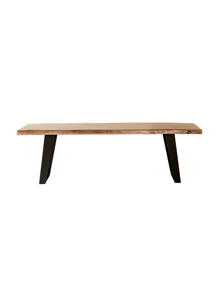 A live edge bench with a solid acacia wood top and iron legs, with a natural finish and raw contours.